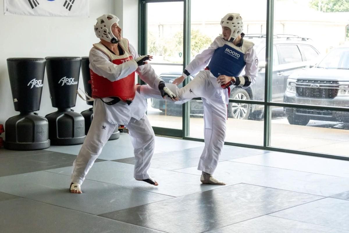 Adult taekwondo students practicing sparring techniques in martial arts class