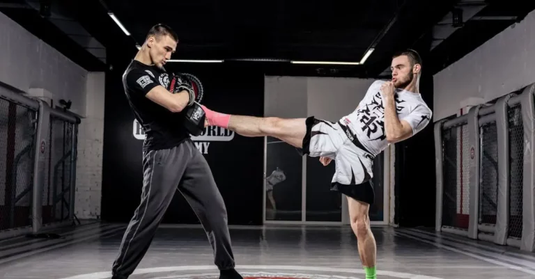 Adult beginner martial arts practicing a controlled high kick with a partner for consistency.