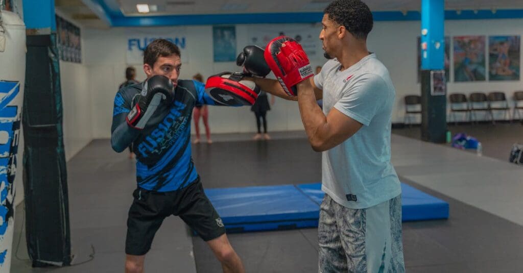 Coach holding pads for striking practice in martial arts for adults.