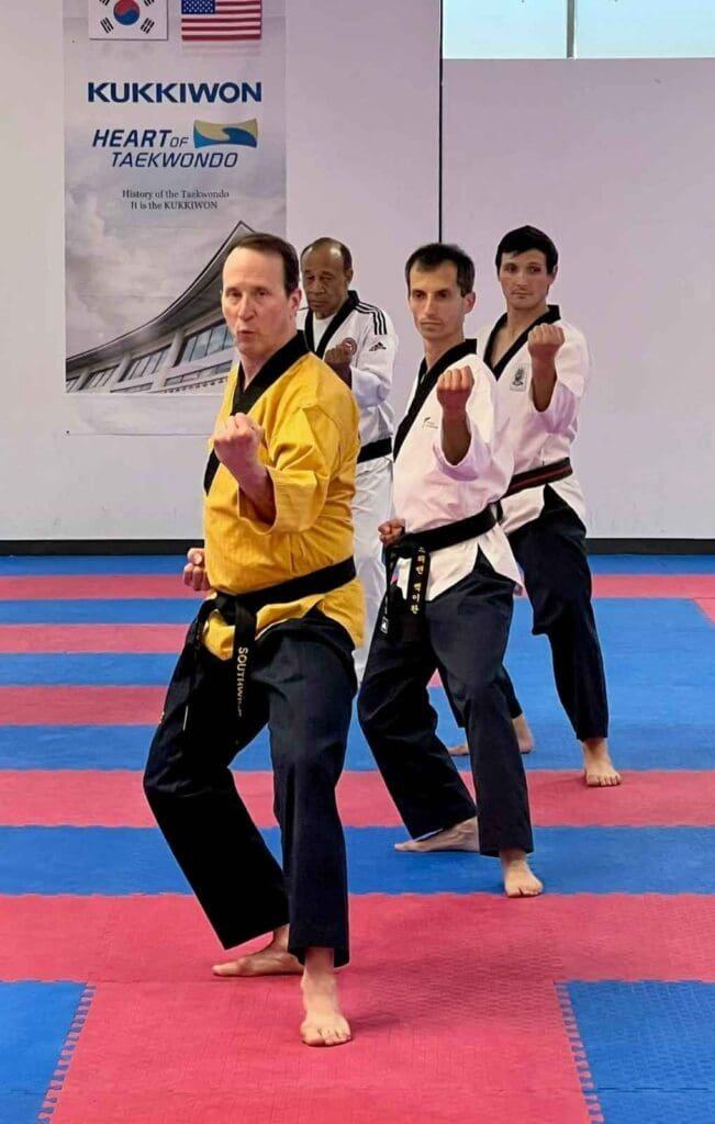 Group of adult black belt practitioners demonstrating traditional punch stances during a formal Taekwondo session martial arts practice habits for beginners